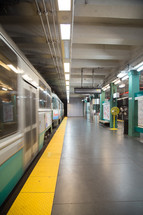 An empty subway station platform next to a subway train.