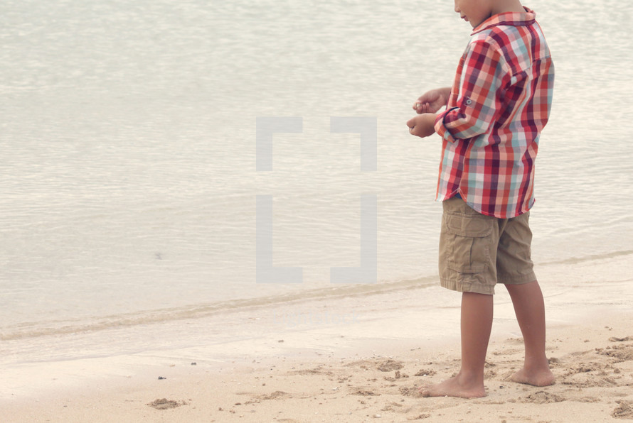 a boy child standing on a beach 