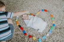 a big brother making a heart around his baby sister with legos 
