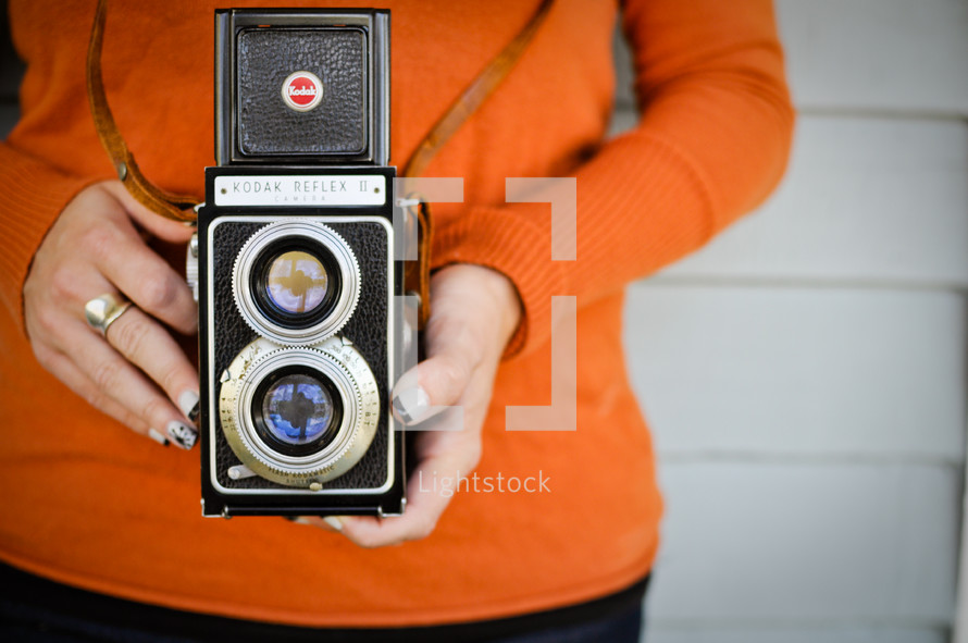 A girl holds a vintage camera.