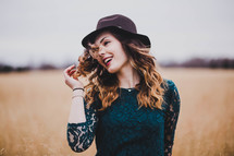 a portrait of a woman in a hat in a field 