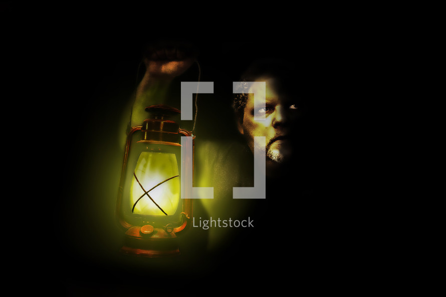 Man holding lantern up in the midst of darkness.