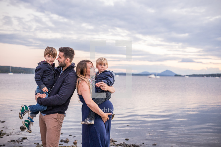 a young family standing by a lake shore 