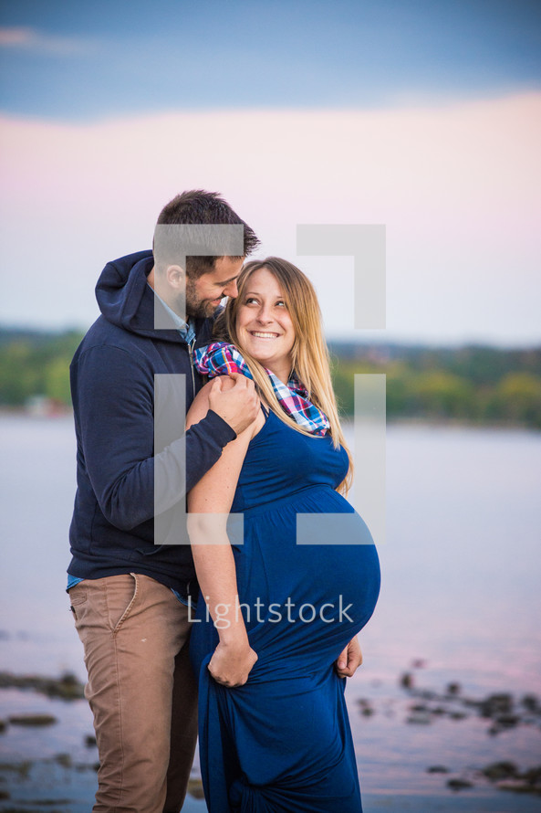 a loving expecting couple standing together outdoors 