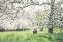 child standing under a spring tree 