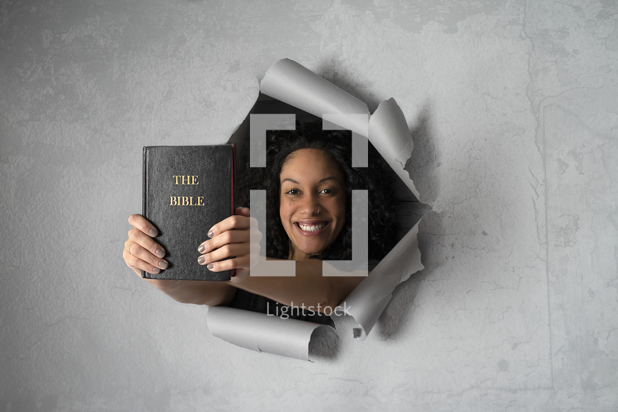 peeking through paper holding a Bible 
