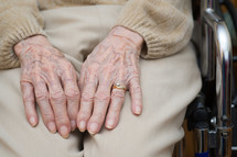 Hands of an elderly person in a wheelchair.