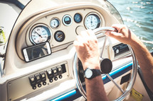 a man with his hands on the steering wheel of a boat 