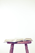 Wooden stool with open Bible on top.
