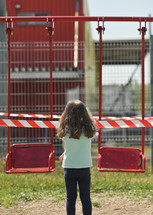 girl standing in front of a closed playground 