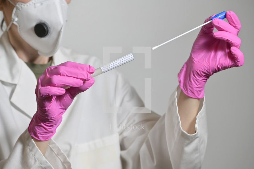 Doctor inserting cotton swab into test tube