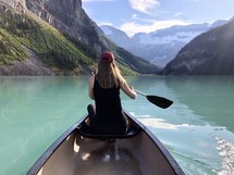 woman in a boat paddling over a lake 