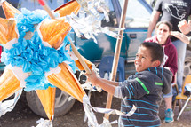 A boy hitting a star shaped piñata.