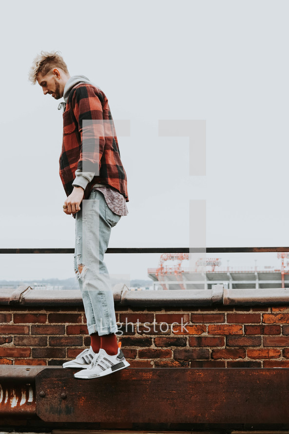 a man on a rooftop balancing on a metal beam 
