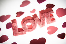 the word LOVE in red glitter Letters and red hearts