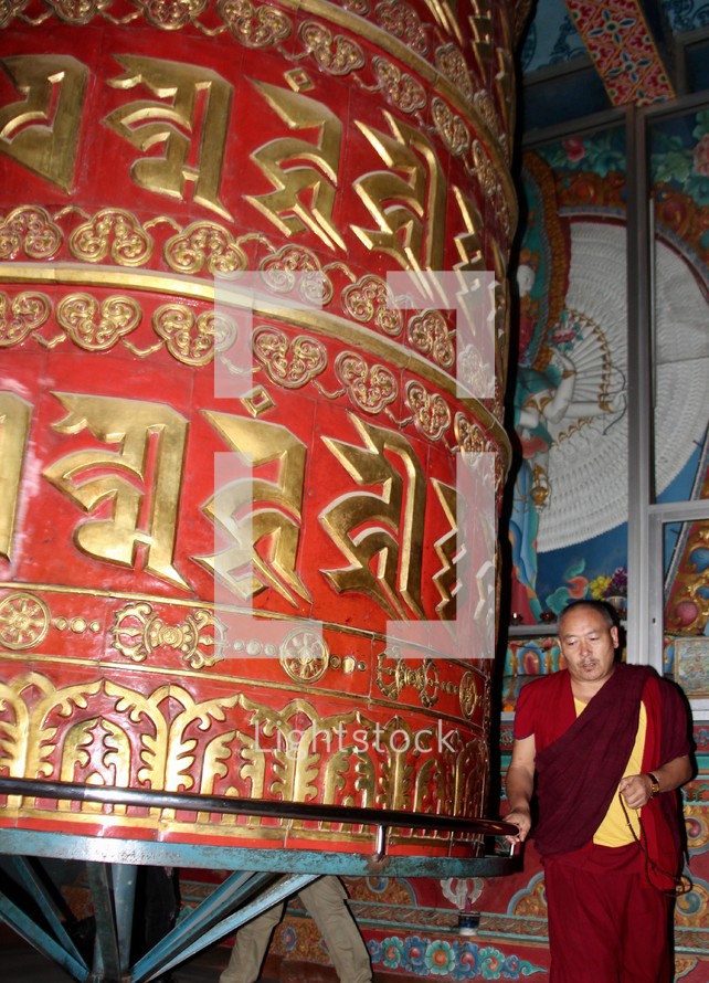 A Tibetan man sends prayers spiralling up to heaven by spinning a Buddhist prayer wheel in Nepal, Asia