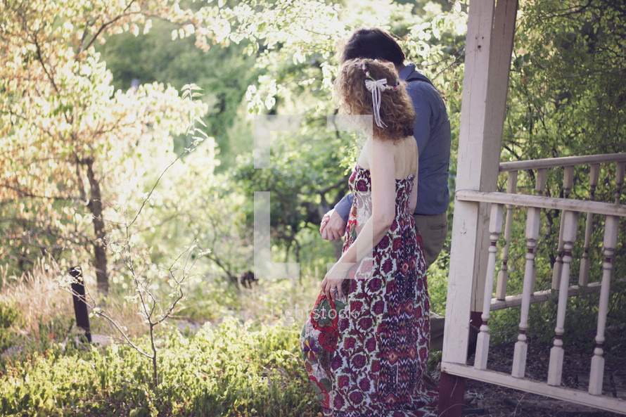 a couple walking holding hands through overgrown vegetation 