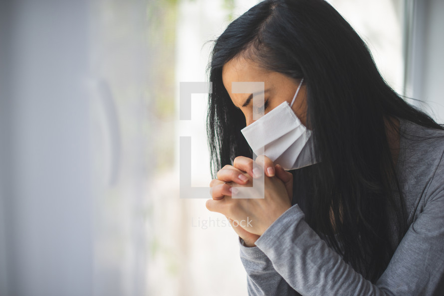 a woman wearing a mask praying 