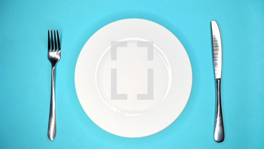 Table setting in restaurant or cafe. Fork and knife. White plate on blue table. High quality photo