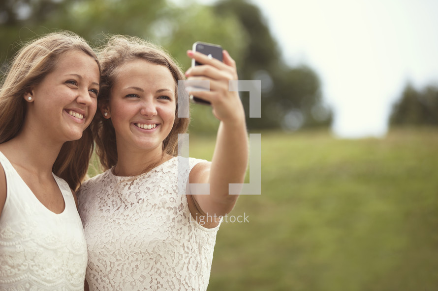 two girls taking a selfie with a cell phone.
