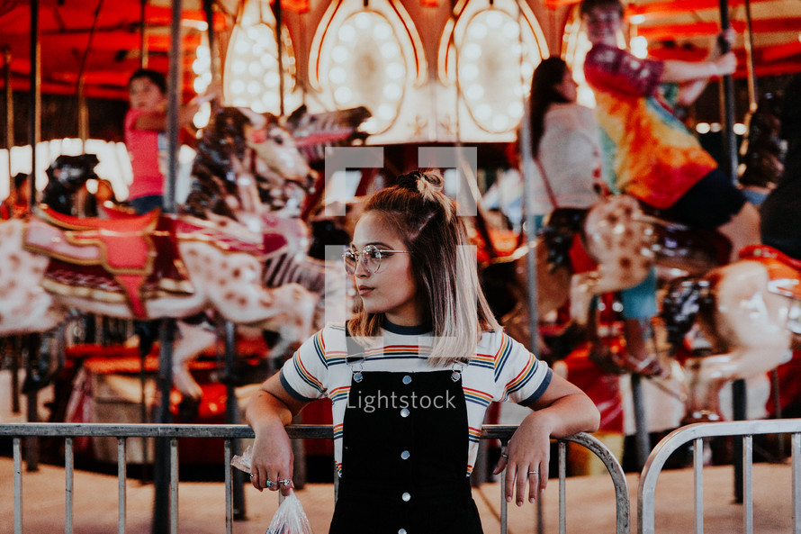 a girl standing in front of a carousel 