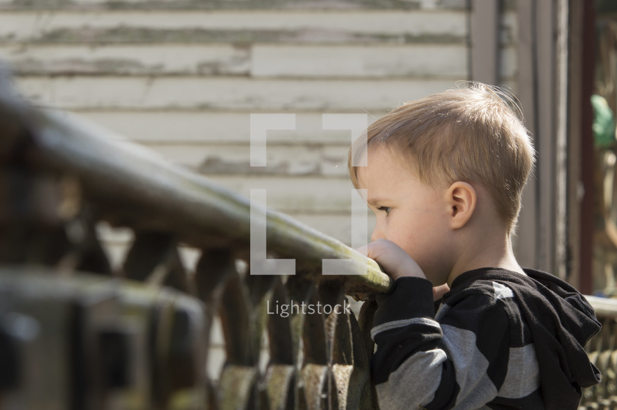 a toddler boy looking over a railing 