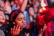 a woman with hands raised and eyes closed during a worship service 