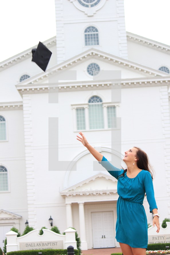 a woman tossing her graduation cap in front of a church 
