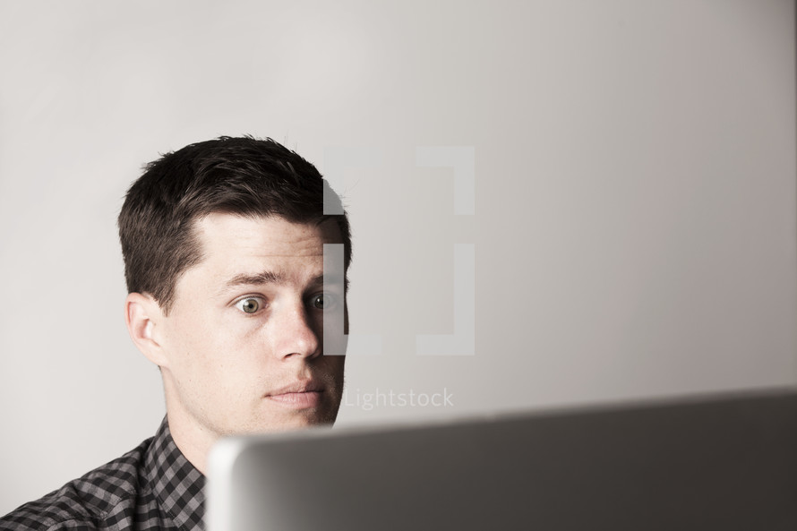 Wide-eyed man looking at a laptop screen.