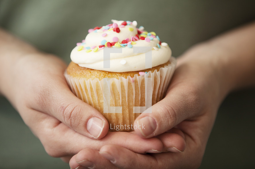 cupped hands holding a cupcake 