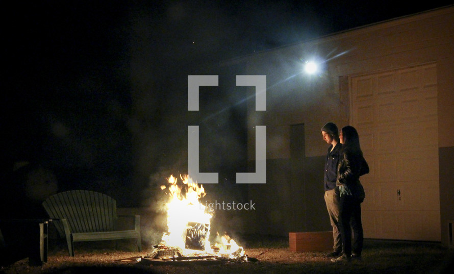 a man and woman standing in front of a fire pit 