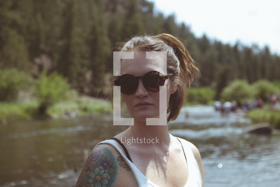 woman standing in a river wearing sunglasses 