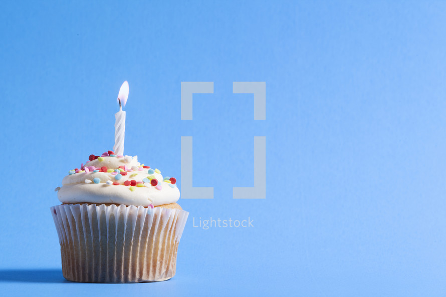cupcake and candle against a blue background 