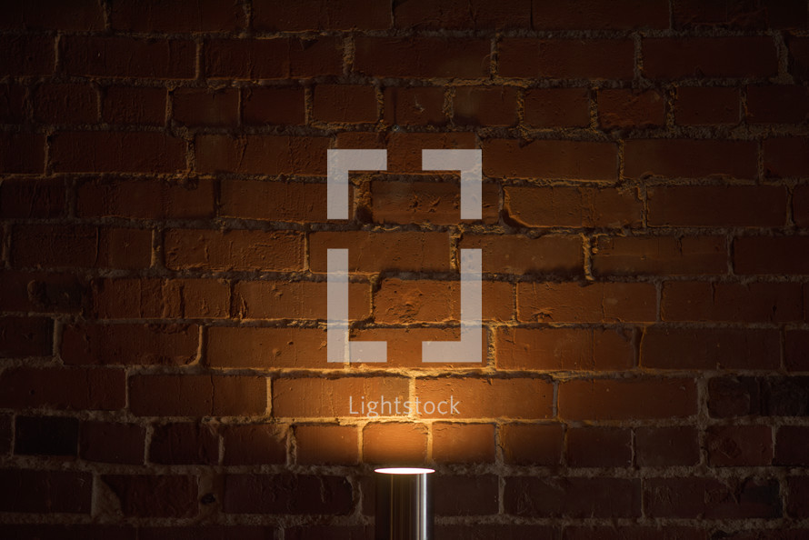 lamp glowing against a brick wall 