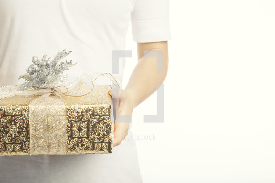 A man holding out a gold and silver wrapped gift with a bow
