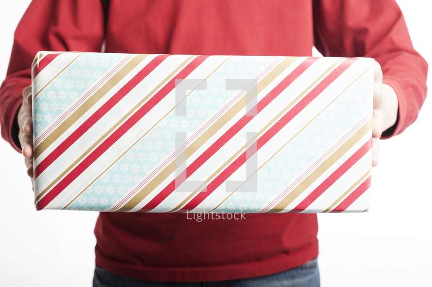 A man holding out gift wrapped in striped wrapping paper