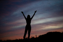 silhouette of a young woman on a mountaintop at sunset 