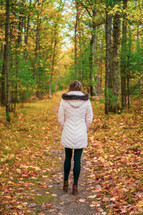 a woman walking on a path in a forest in fall 