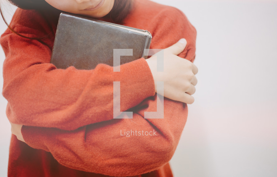 a woman hugging a Bible 