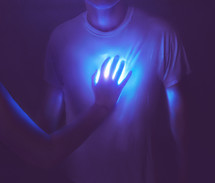 Man with hand over his glowing heart 