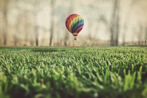 hot air balloon landing in the green grass