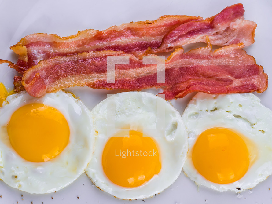 Fried egg with bacon on white plate. Delicious colorful English breakfast. High quality photo