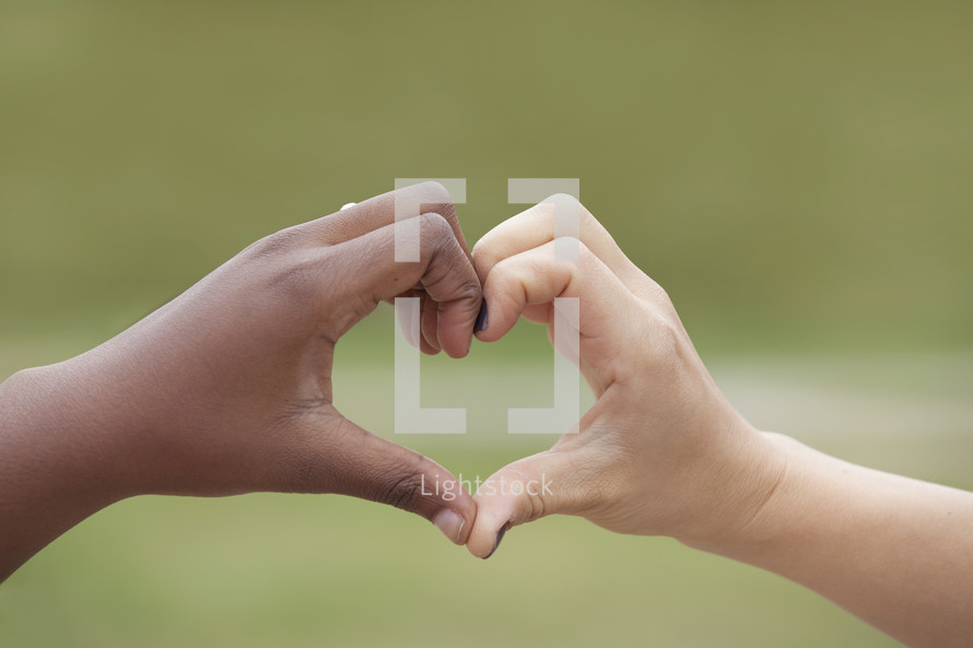 hands from two different races forming a heart shape 