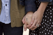 a couple holding hands, cross tattoo 