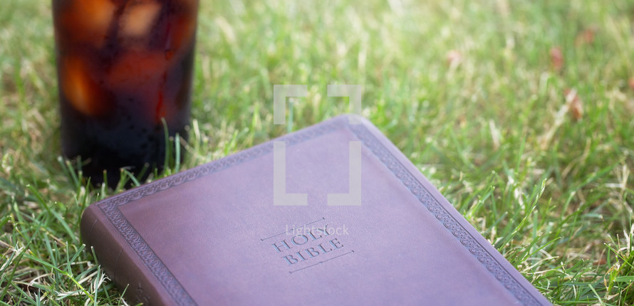 Bible and drink on grass