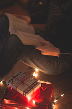 a man reading a Bible near Christmas gifts 