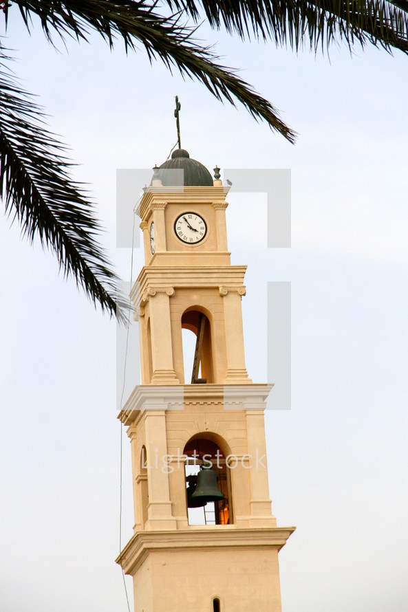 A church steeple with a cross, clock, and bell tower.