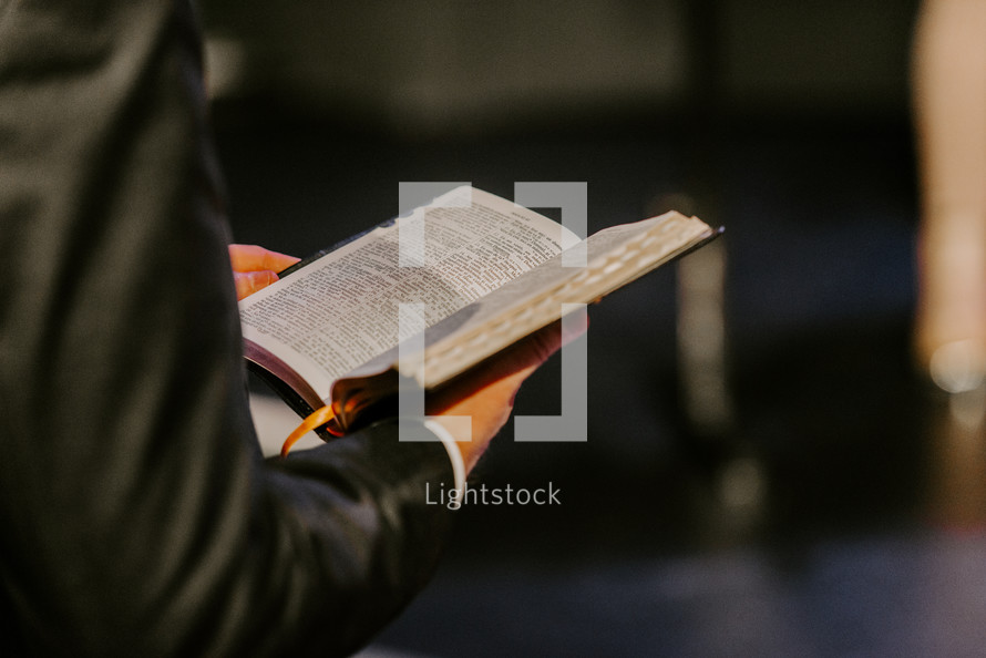 Close up of hands holding an open Bible.