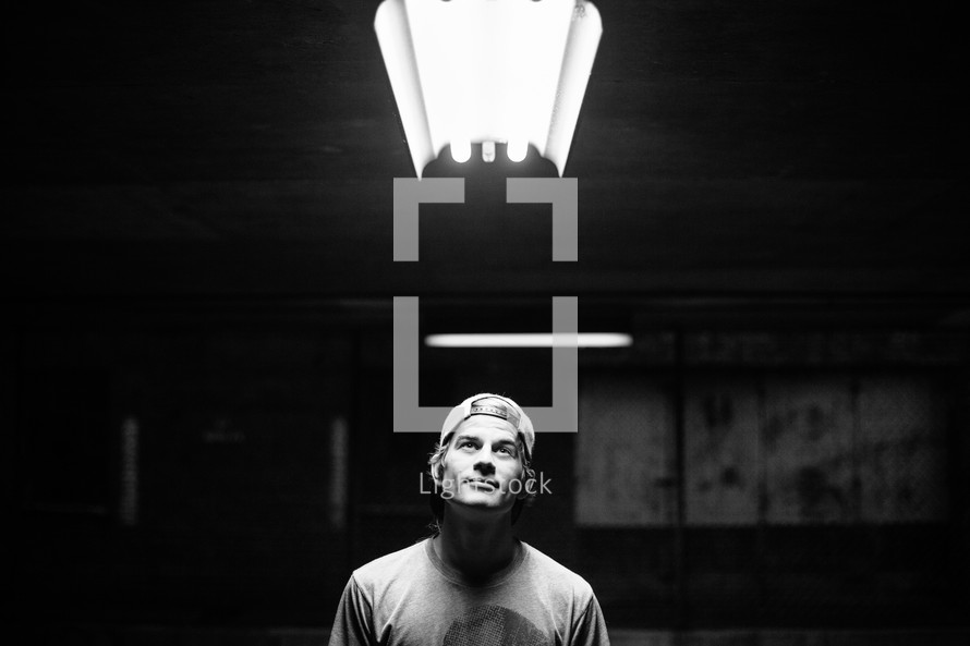 man standing in sunlight in a dark warehouse 