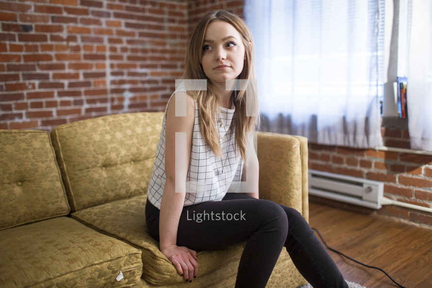 a woman sitting on a couch thinking 